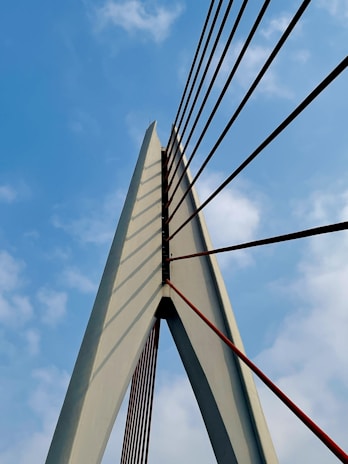 A panoramic view of a massive cable-stayed bridge under construction against a clear sky.