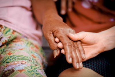 Hands of an elderly person and a child sharing ginguba in a warm, sunlit setting.