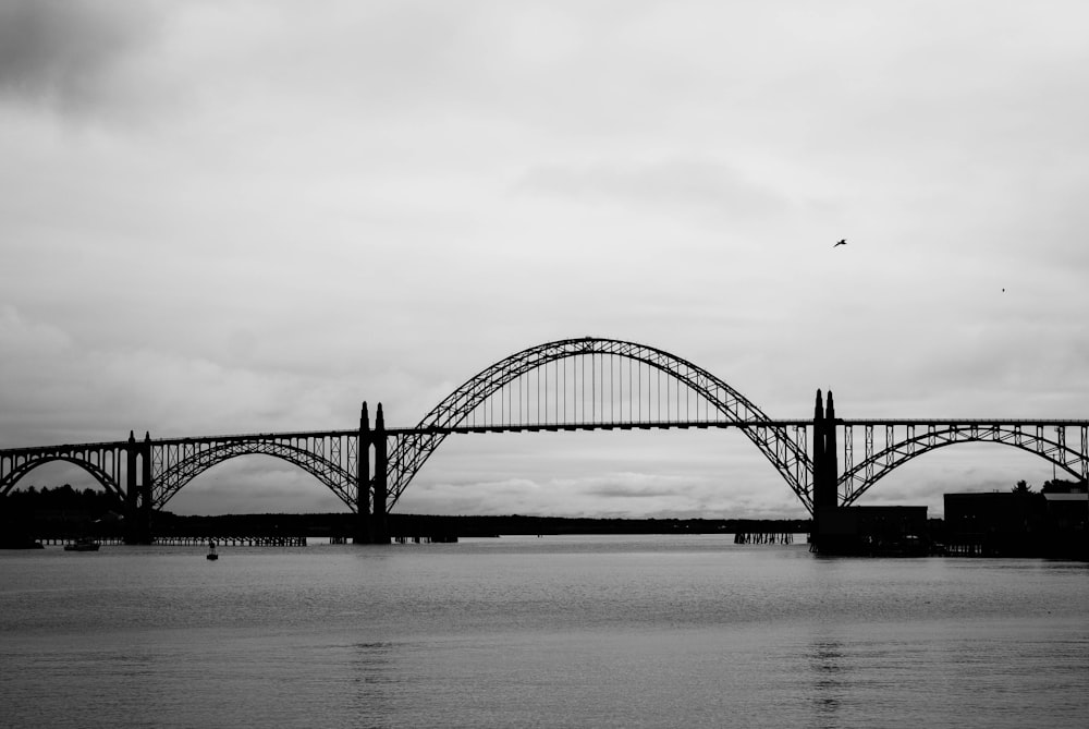 a black and white photo of a bridge over water