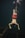 A person is diving underwater, wearing a snorkel and fins. They are swimming over a submerged structure, possibly a shipwreck, in the ocean. The water is dark, and the person's red shorts stand out against the deep greenish-blue surroundings.