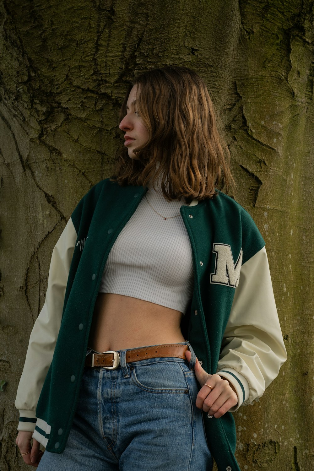 a woman standing next to a tree wearing a green and white jacket
