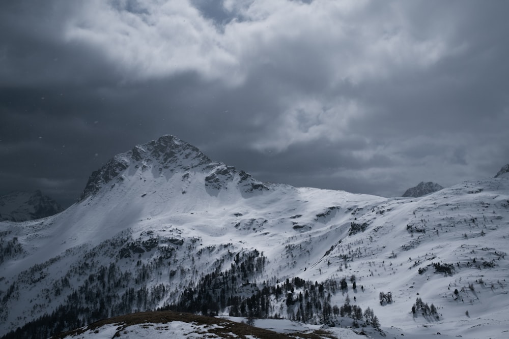 a mountain covered in snow under a cloudy sky