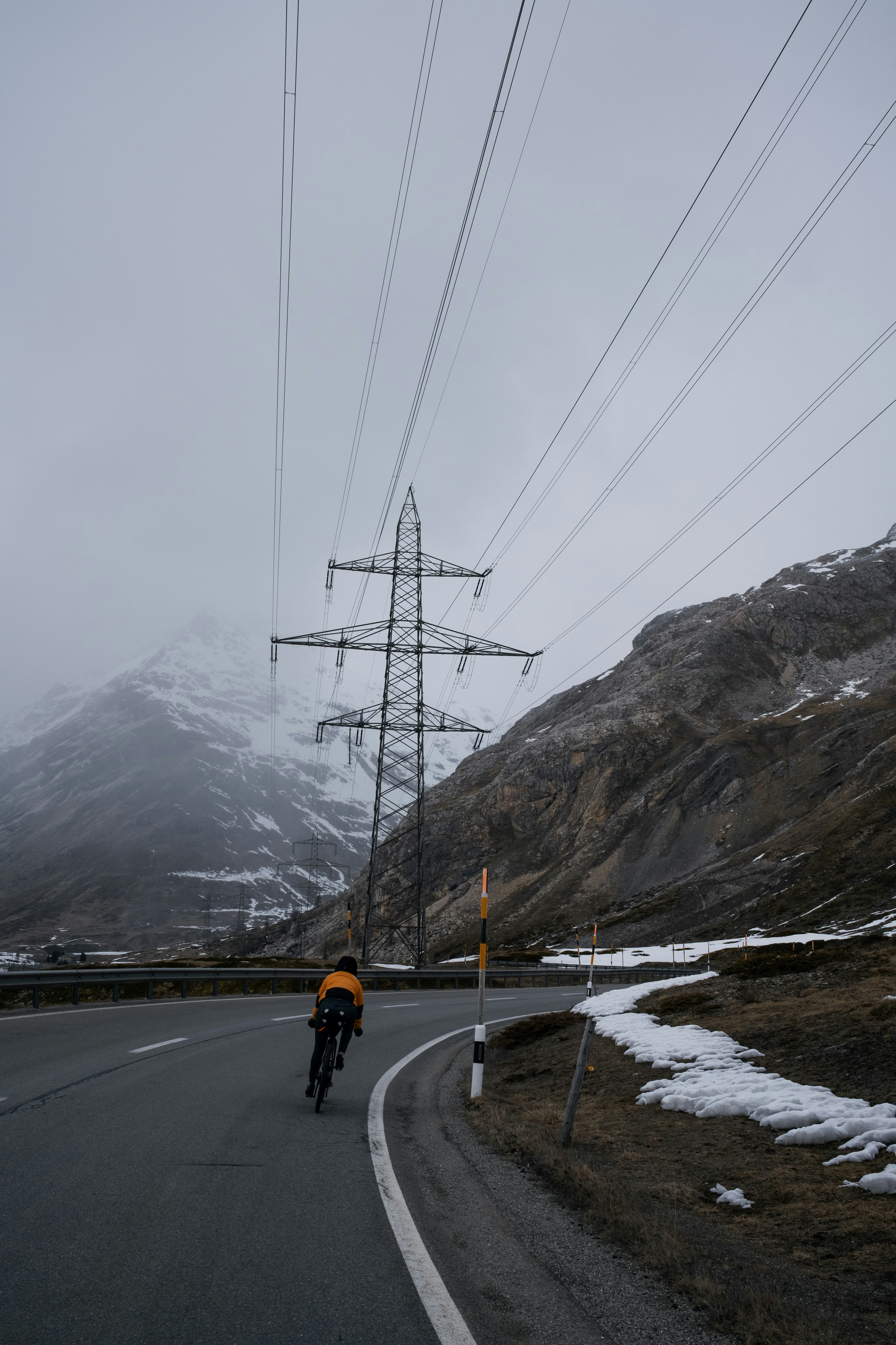 送電線の下の道路を自転車で走る男