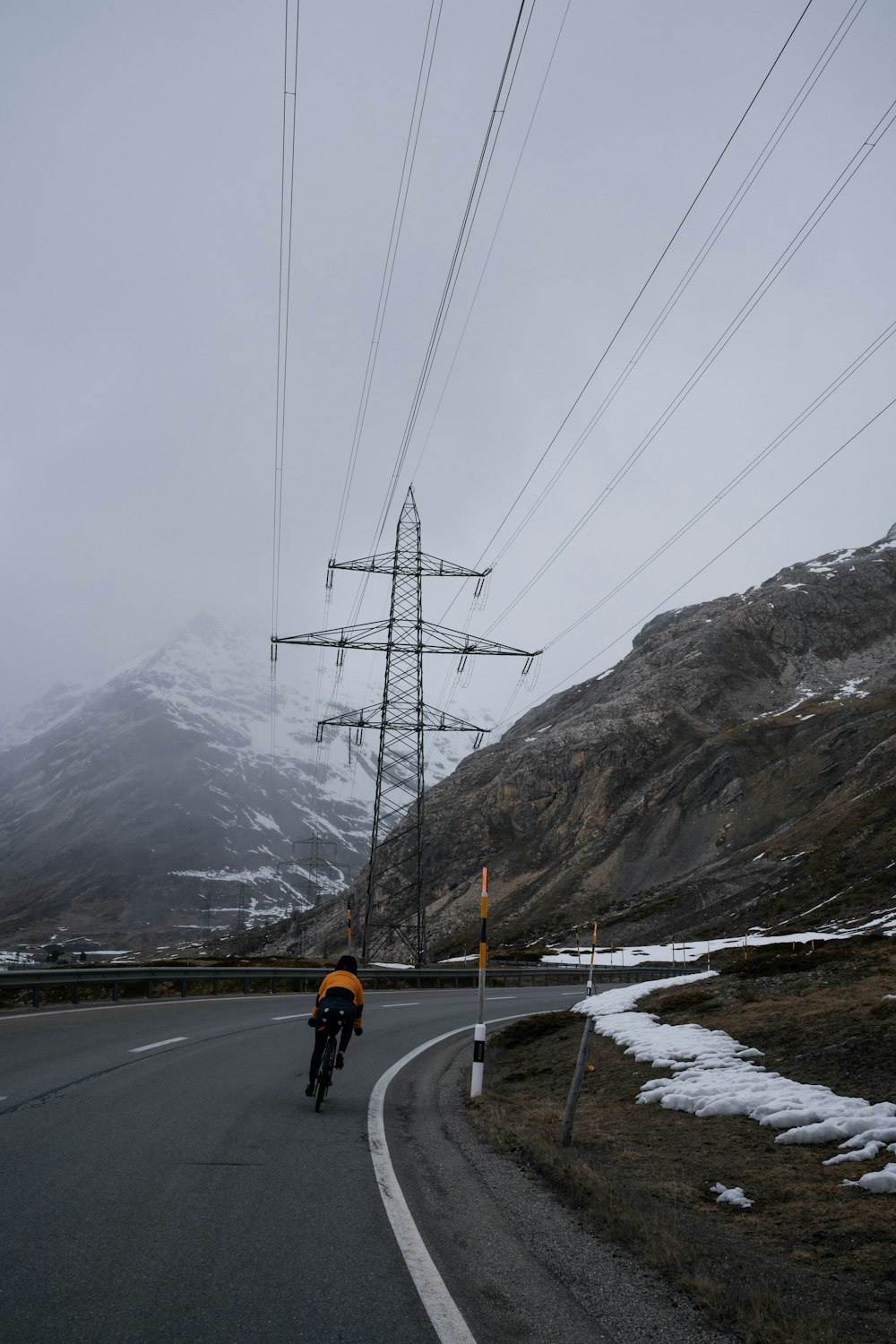 a man riding a bike down a road under power lines
