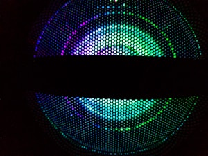 Circular array of vibrant LED lights featuring a pattern of green, purple, and blue colors and a horizontal dark band across the center.