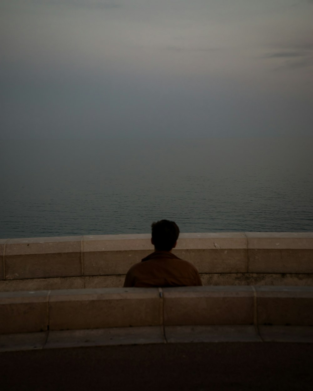 a person sitting on a bench looking at the ocean