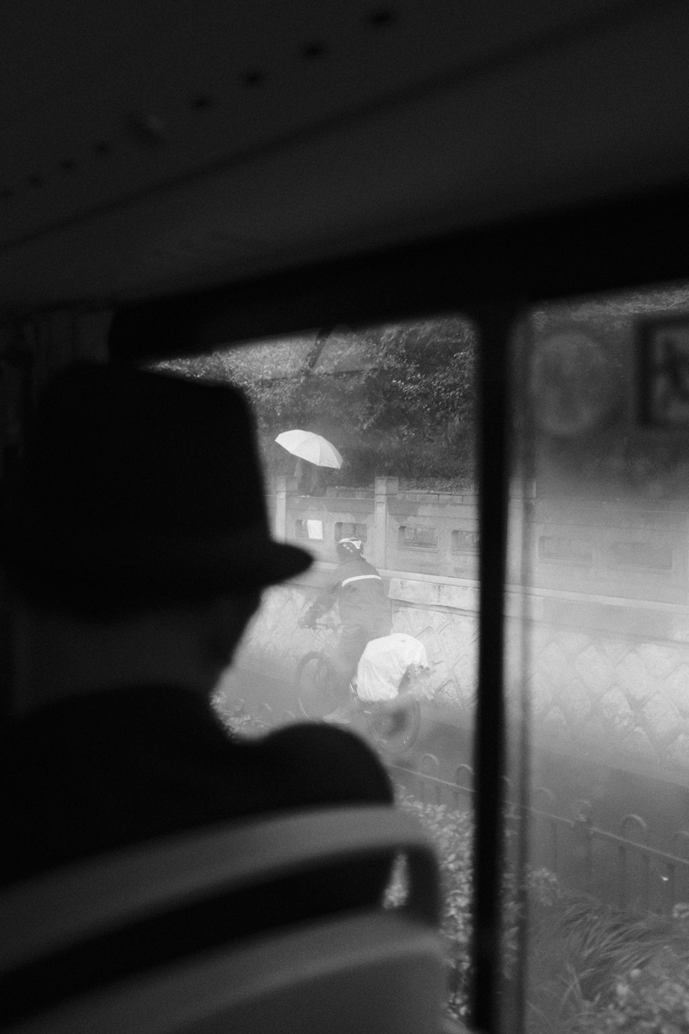 a black and white photo of a person looking out a window