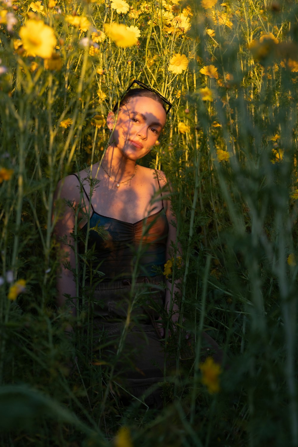 uma mulher sentada em um campo de flores amarelas
