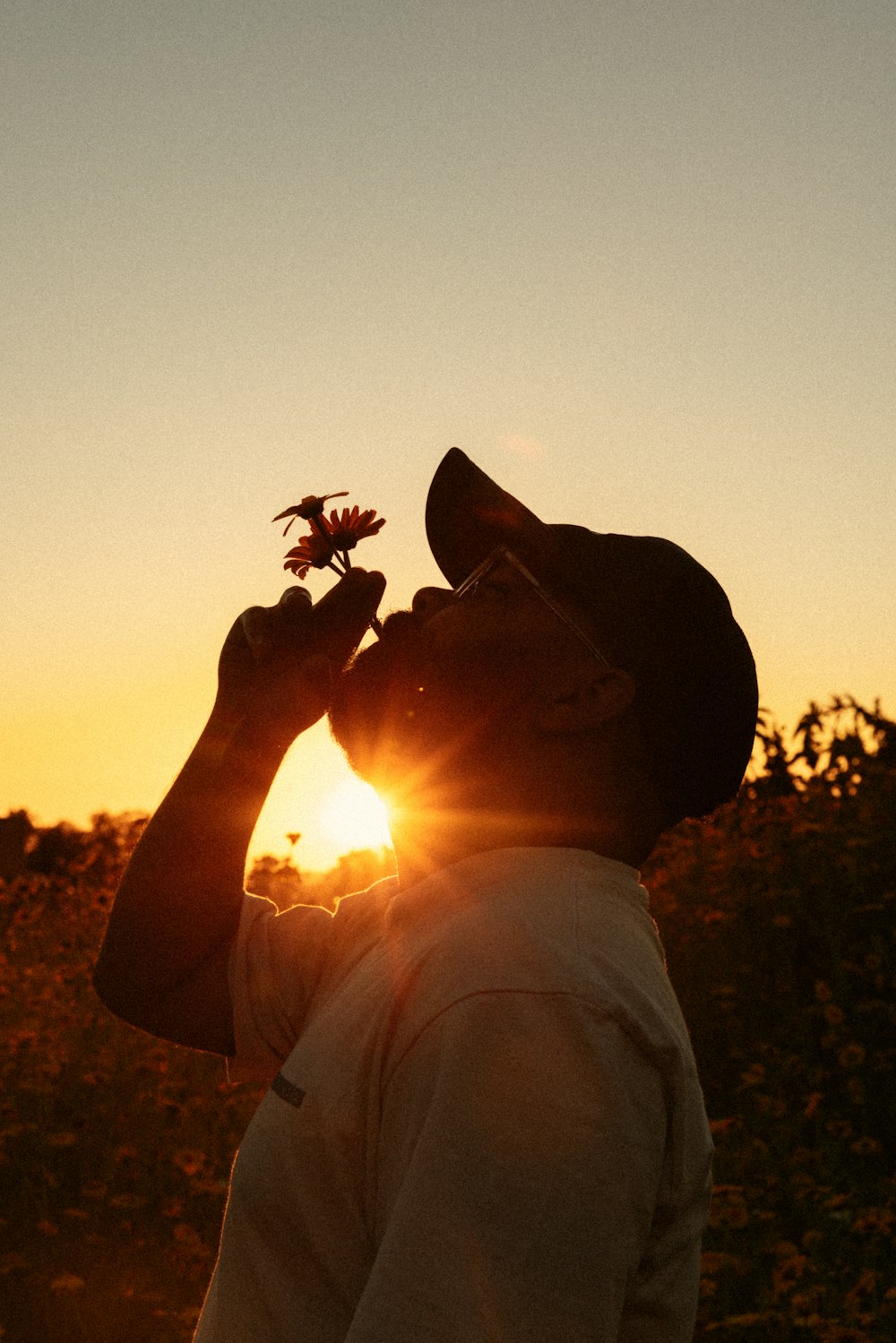 um homem de pé em um campo com uma flor na mão