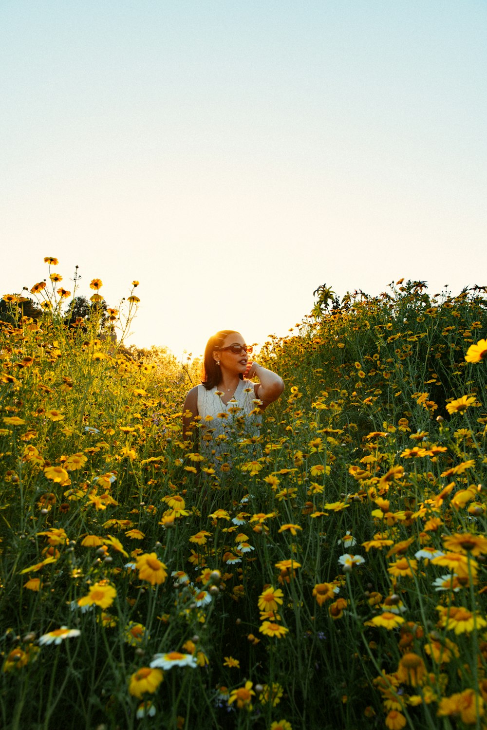 a woman sitting in a field of yellow flowers