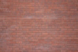 Bricklayer carefully building a wall with red bricks