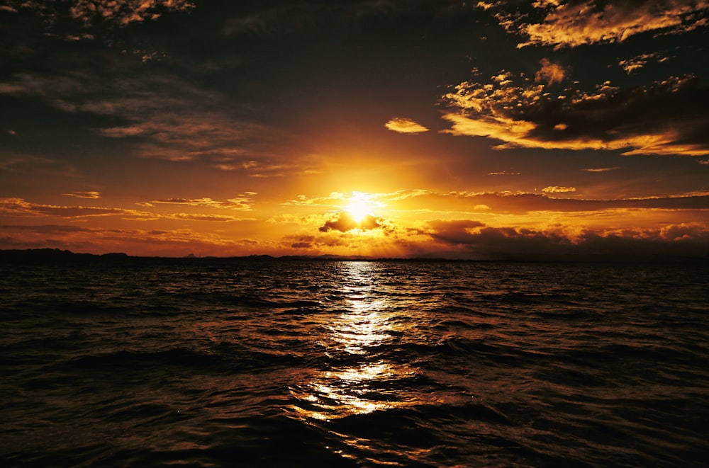 a sunset over a body of water with clouds