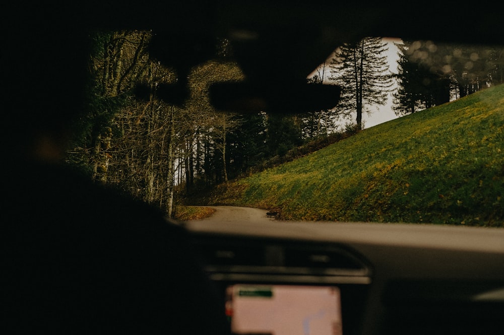 a car driving down a road next to a lush green hillside