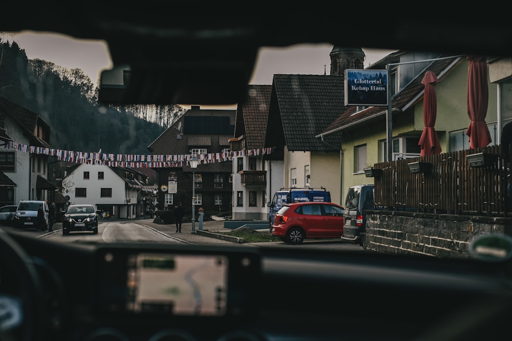 a red car driving down a street next to tall buildings