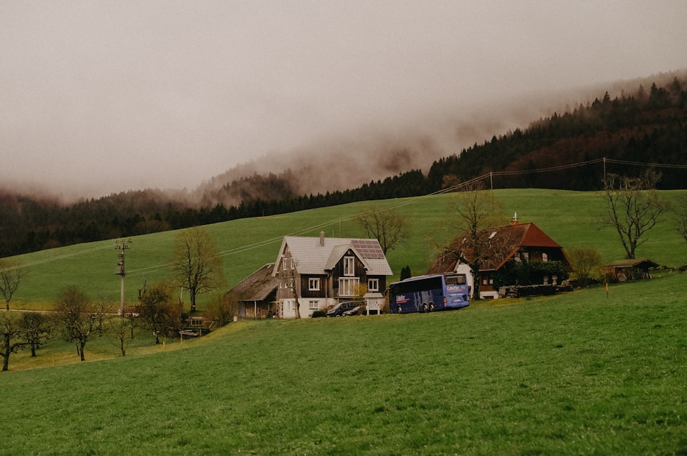 a green field with a house and a truck parked in front of it