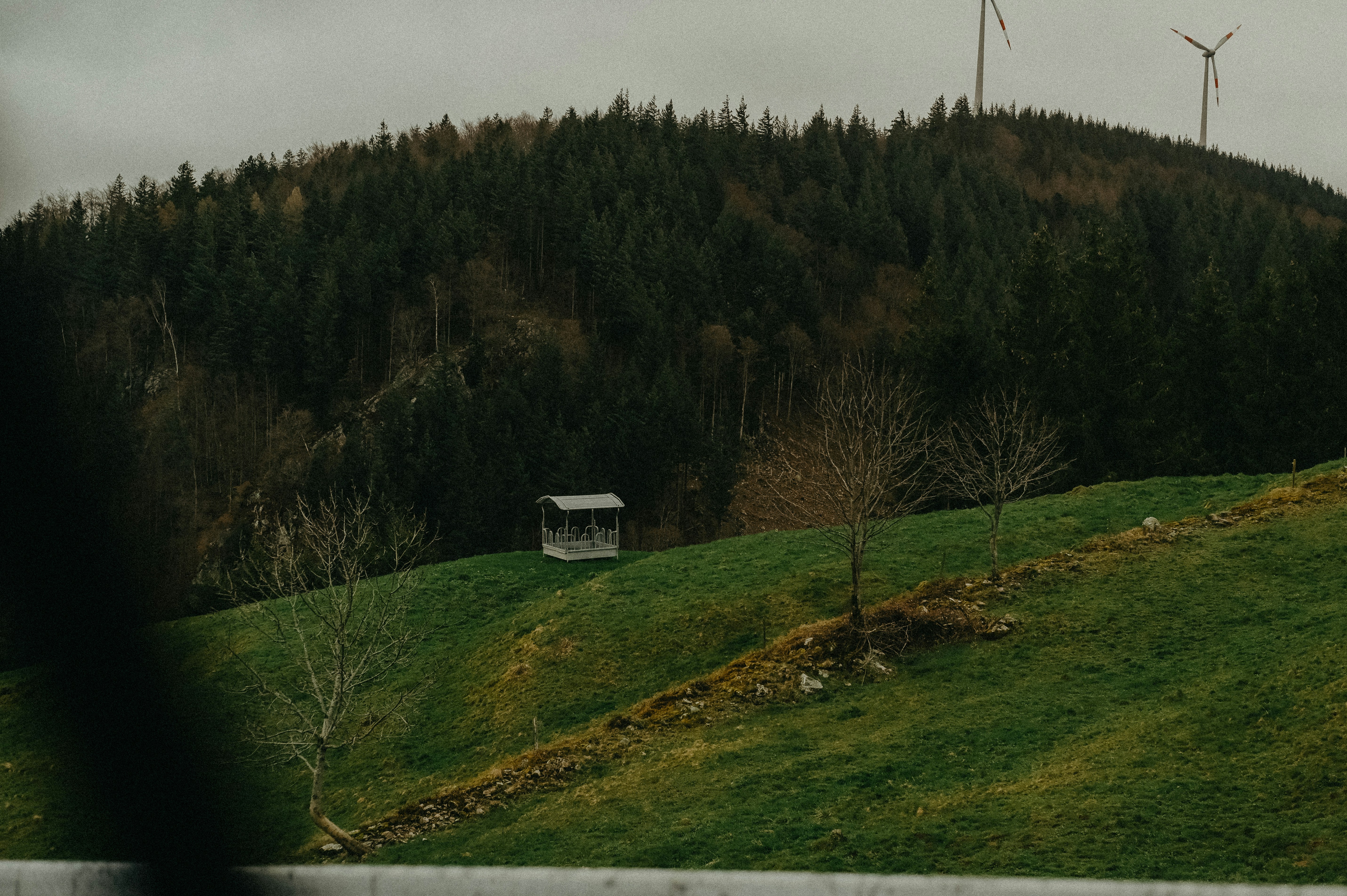 a house on a hill with wind mills in the background