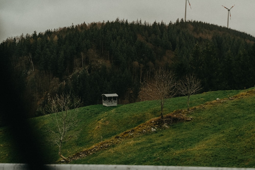 a house on a hill with wind mills in the background