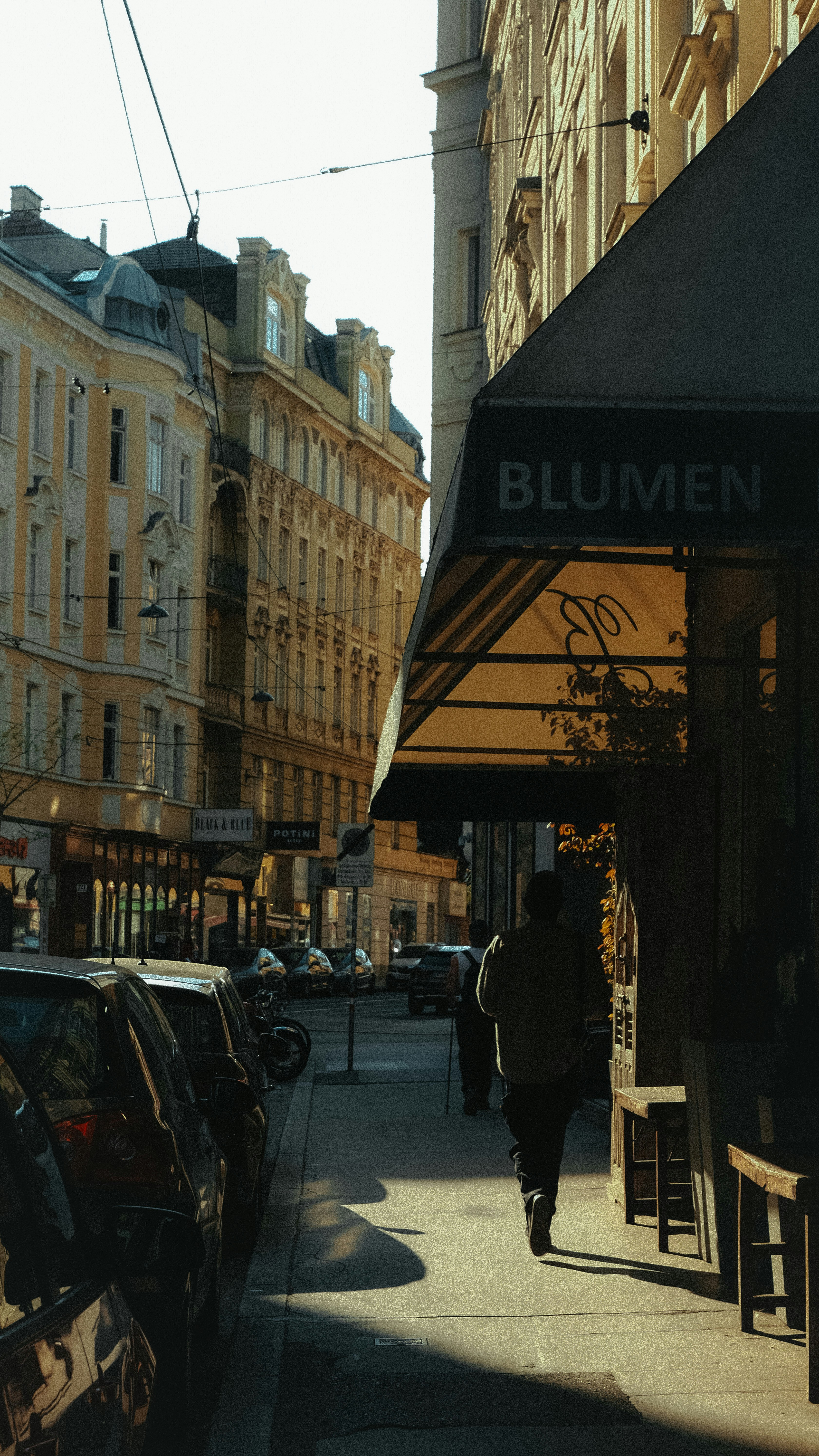 a woman walking down a street next to tall buildings
