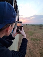 Traveler capturing the sunrise with a camera from a jeep viewpoint.