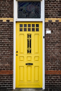 A cheerful yellow front door contrasting with a classic brick facade.
