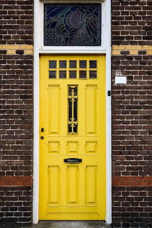 A cheerful yellow front door contrasting with a classic brick facade.