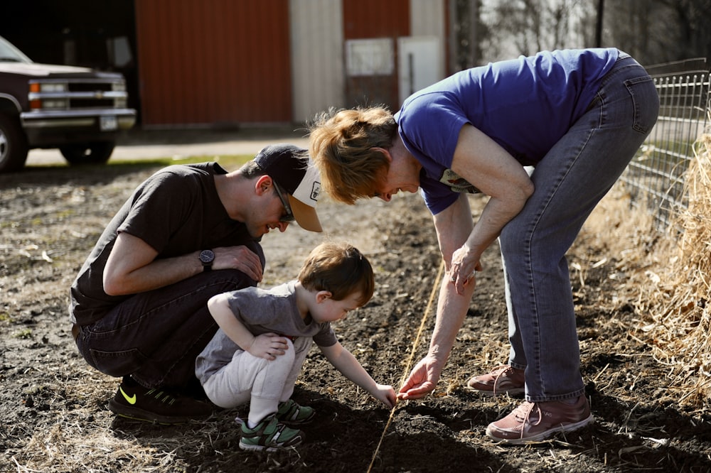 a woman and two children are looking at a plant