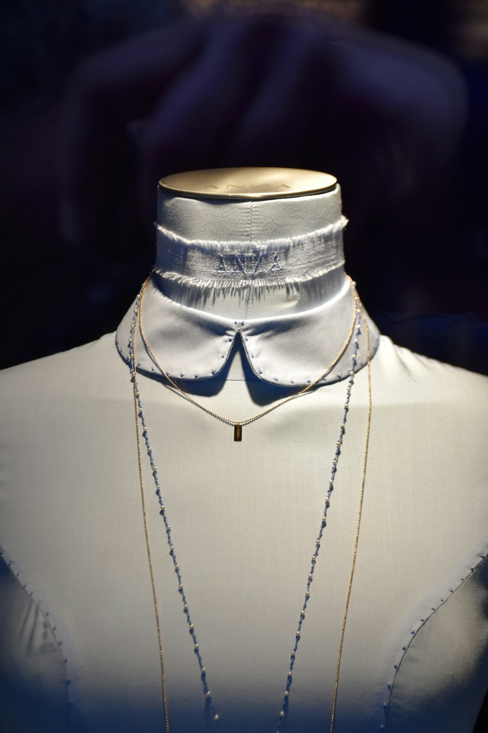 a mannequin wearing a white shirt and a necklace