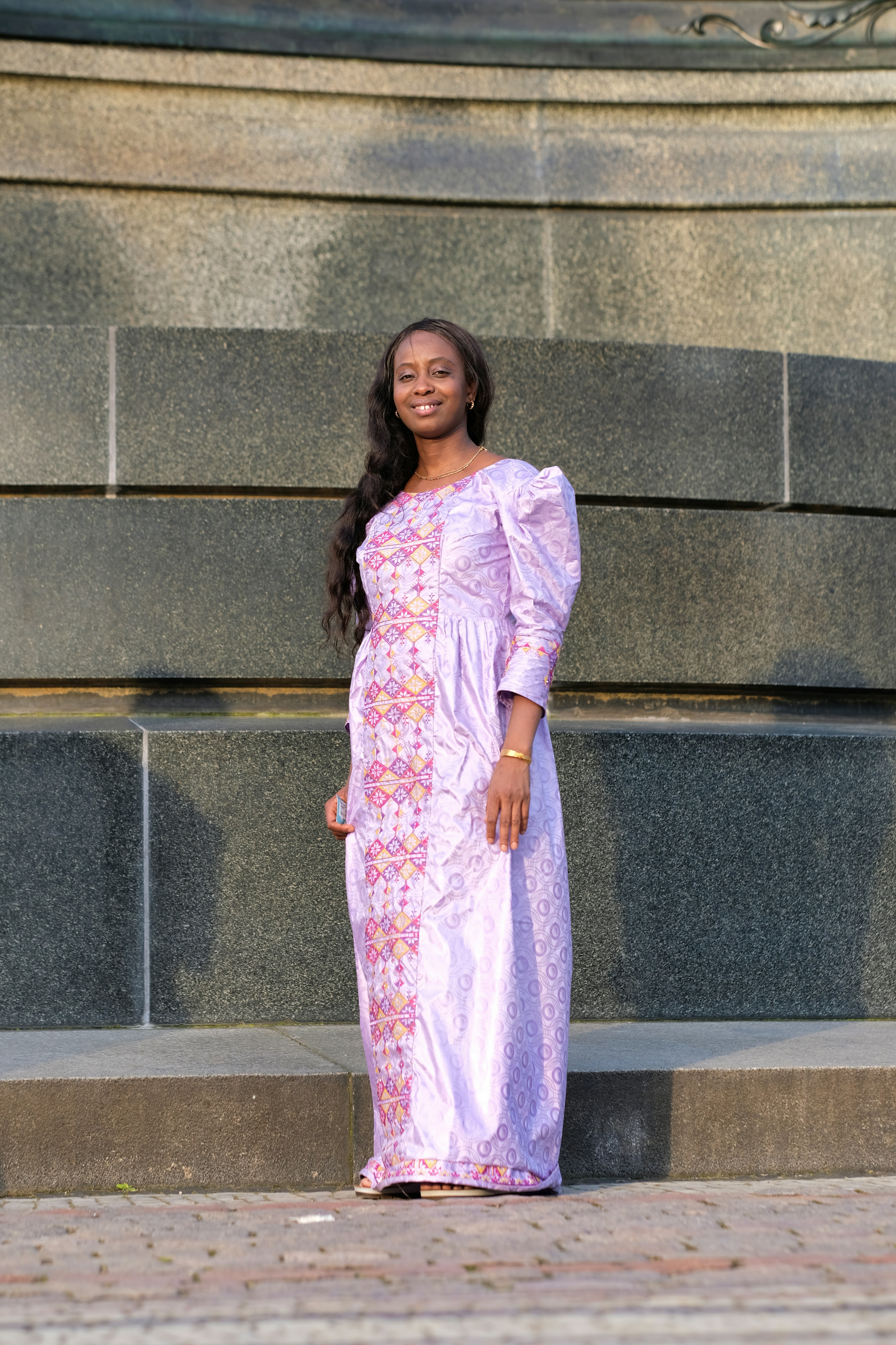 a woman standing in front of a stone wall