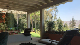 Spacious covered terrace surrounded by lush greenery and vineyard scenery.
