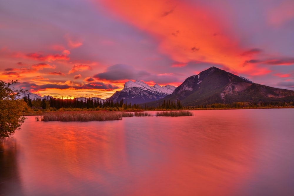 a beautiful sunset over a lake with mountains in the background