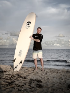 Experienced surfer receiving personalized advice while holding a surfboard near the ocean.