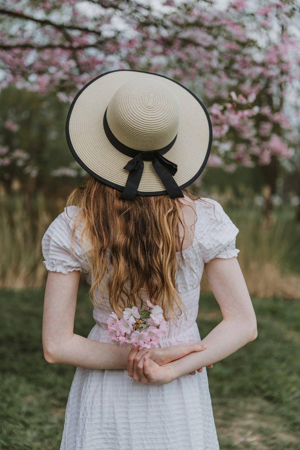 eine Frau, die einen Hut trägt und eine Blume hält