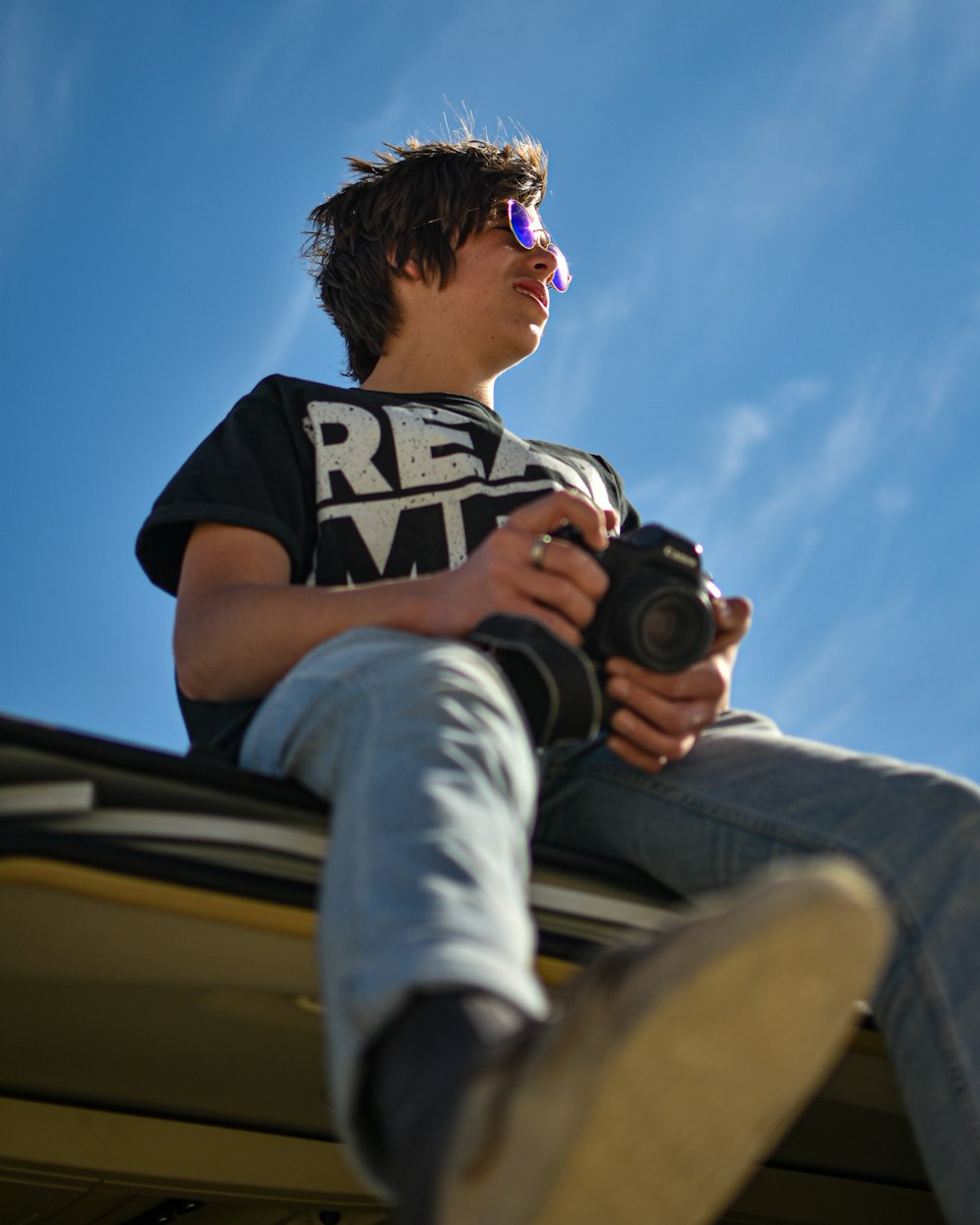 a man sitting on top of a roof holding a camera