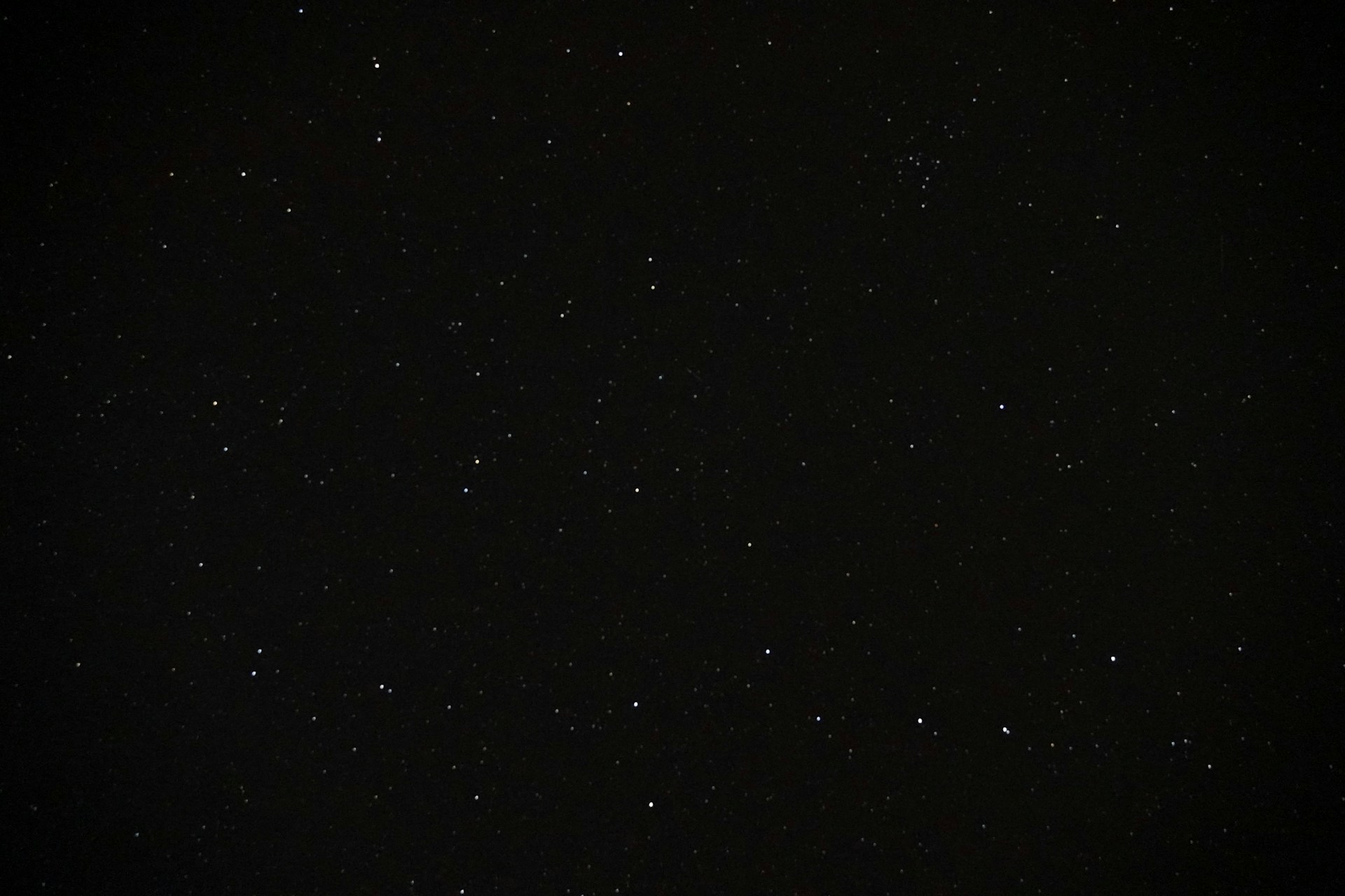 a night sky with stars and a plane in the distance