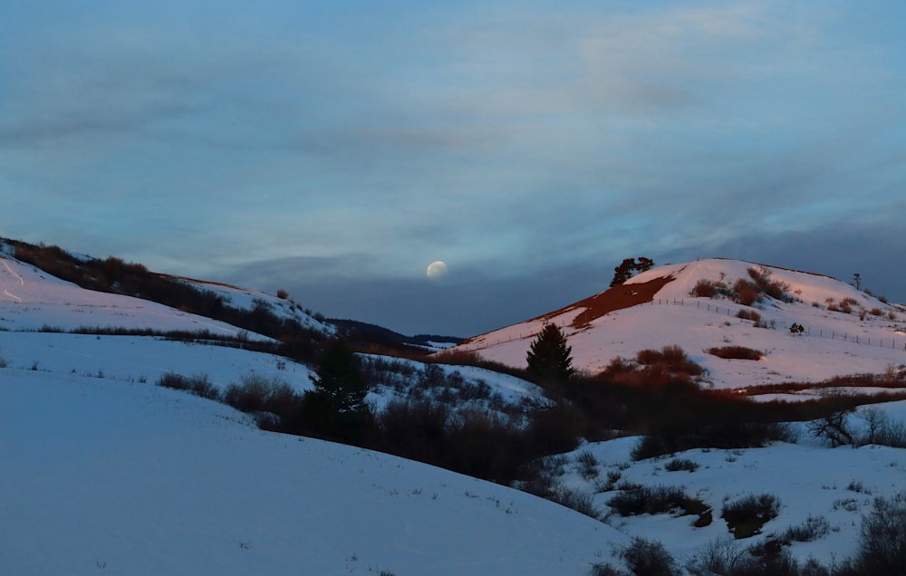 a snow covered mountain with a full moon in the distance