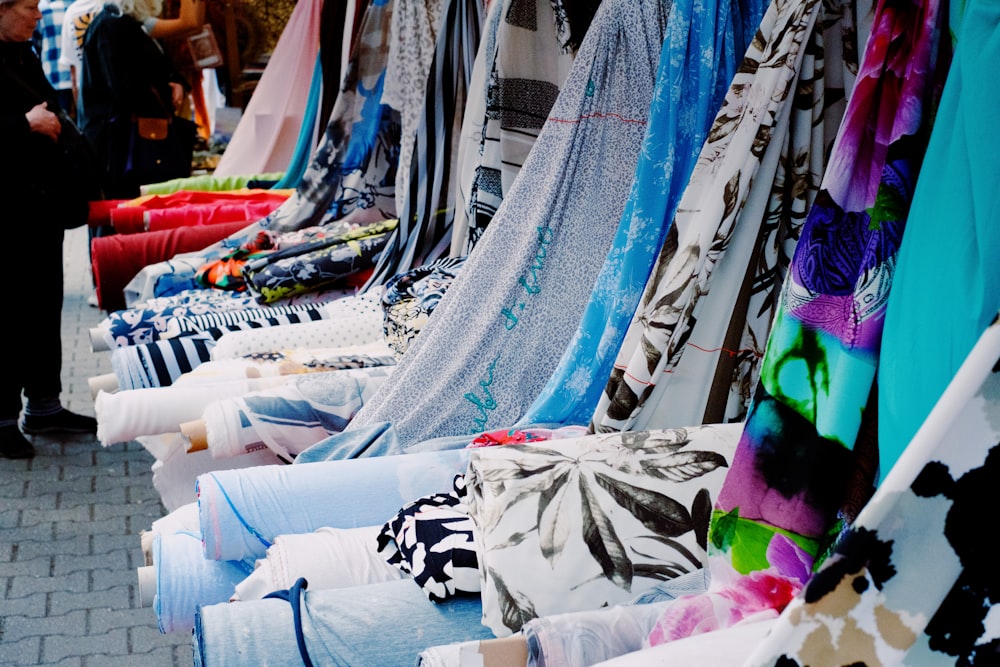 a row of colorful scarves on display on a sidewalk
