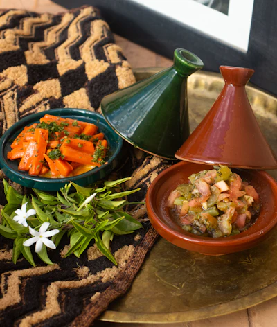 A traditional Moroccan tagine dish served at the table, ceramic conical lid beside it