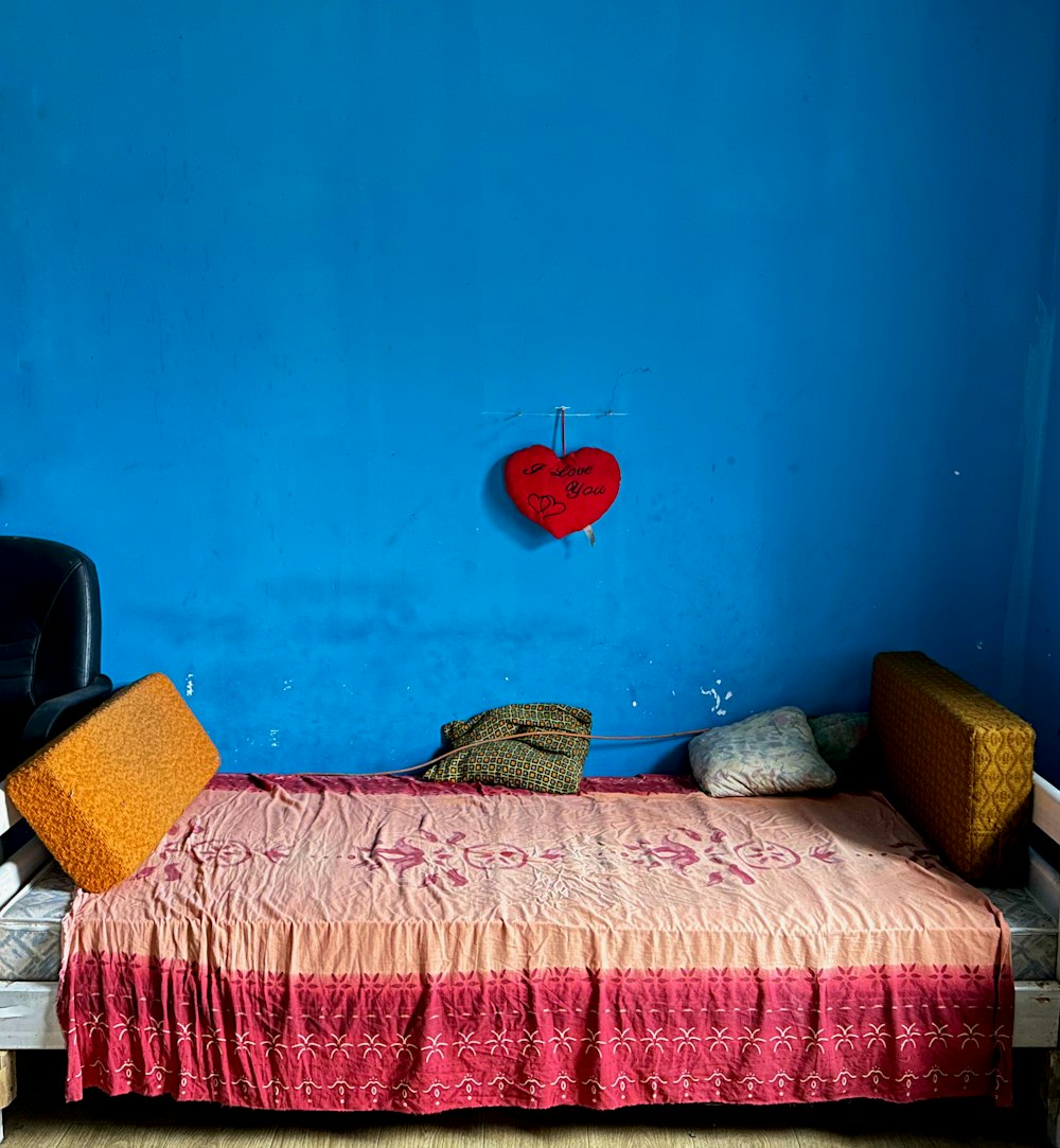 a bed with a red heart on a blue wall