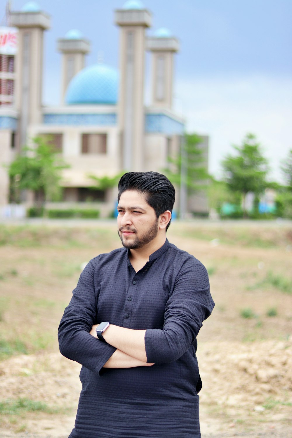 a man standing with his arms crossed in front of a building