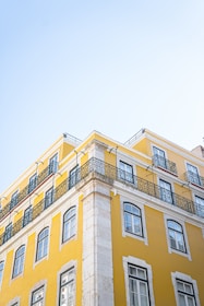 a tall yellow building with balconies on top of it