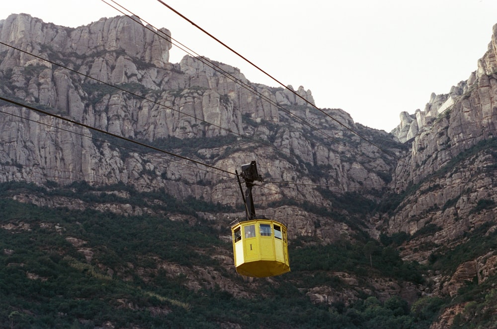 a yellow cable car going up a mountain side