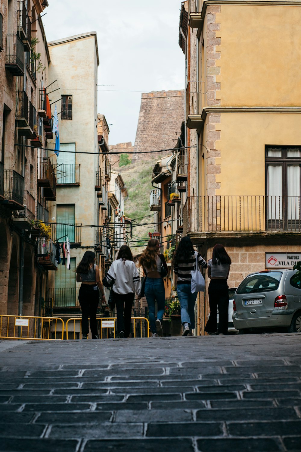 a group of people walking down a street next to tall buildings