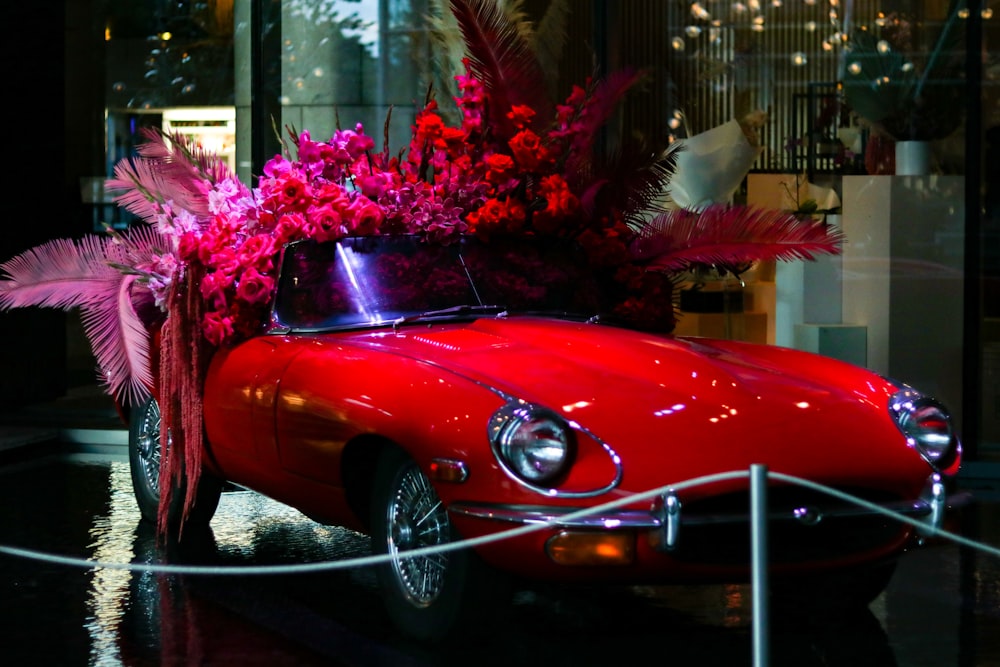 a red car with a bunch of flowers on top of it