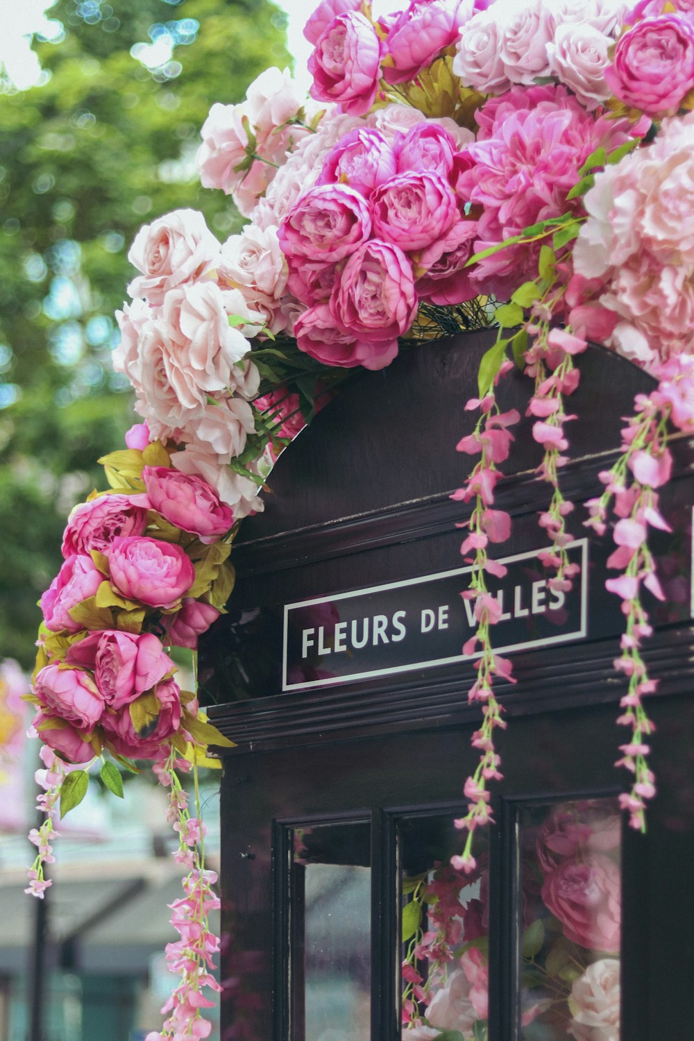 a black phone booth with pink flowers on it