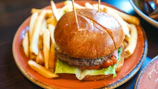 A juicy hamburger with crispy golden fries on a rustic wooden table.