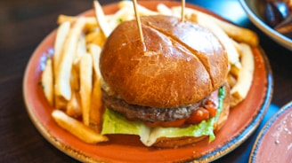A rustic wooden table with a juicy classic hamburger, crispy fries, and a fresh green salad beautifully arranged.