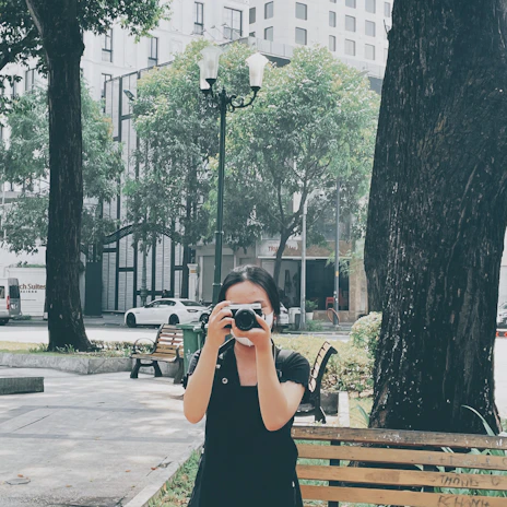 A stylish lifestyle blogger taking photos in a chic urban park with modern sculptures.