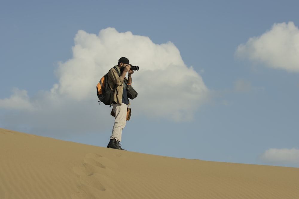 a man standing on top of a sand dune