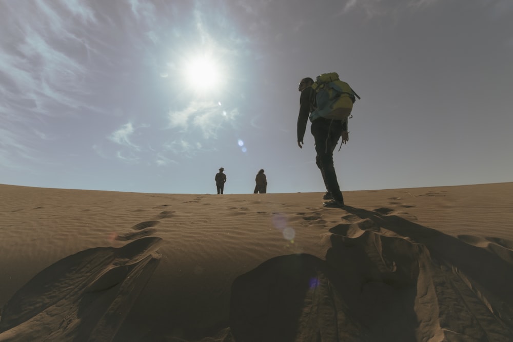 a group of people walking across a sandy field