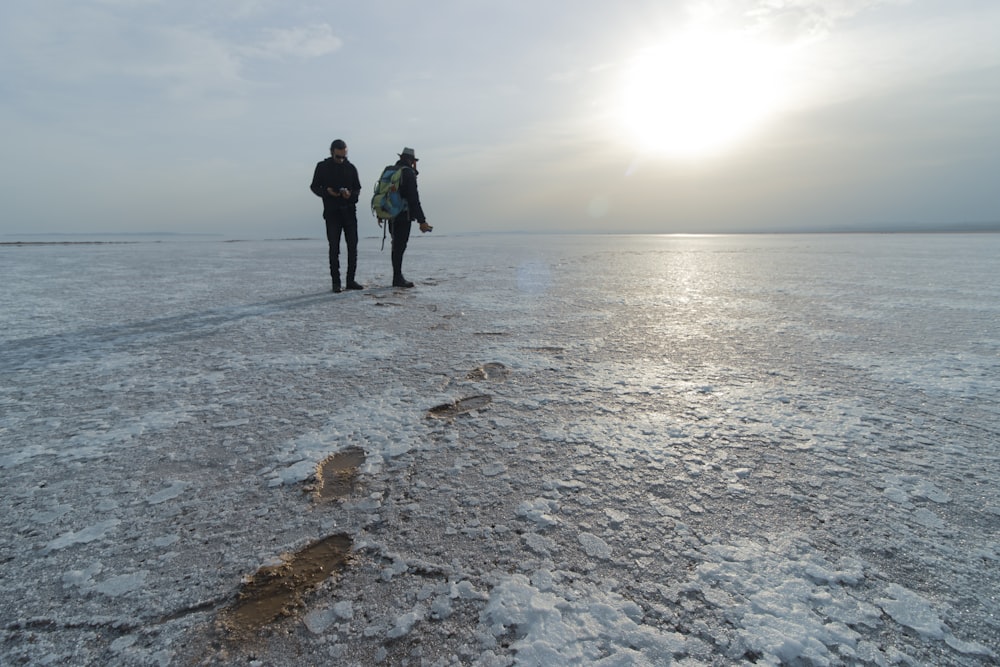 a couple of people standing on top of a frozen lake